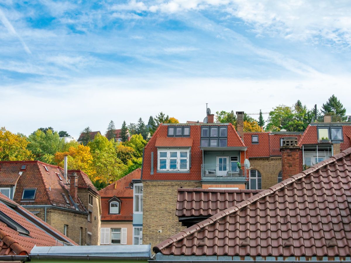 Rote Ziegeldächer von Wohnhäusern mit Dachfenstern unter blauem Himmel