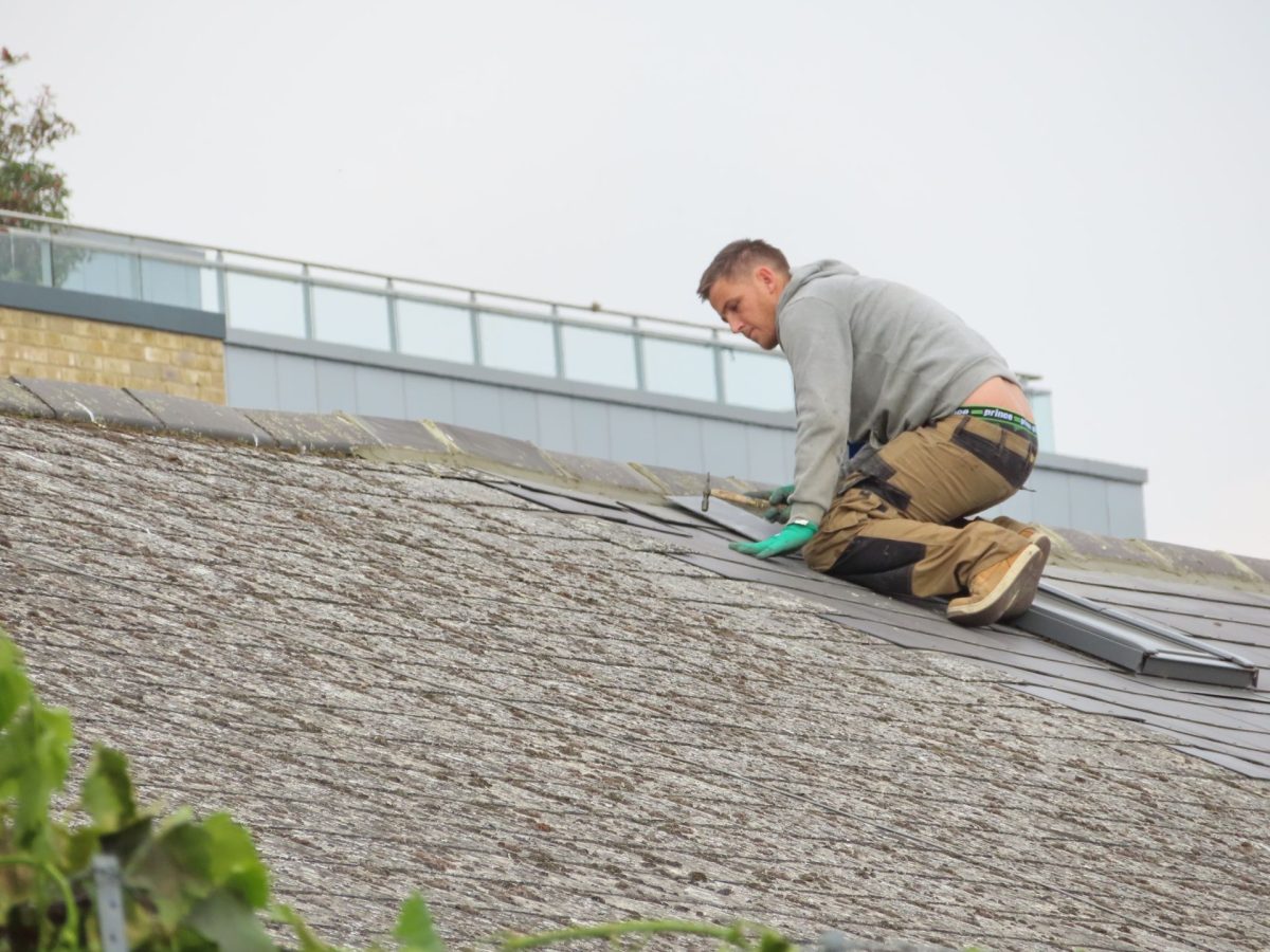 Dachdecker kniet bei der Arbeit auf einem geneigten Dach